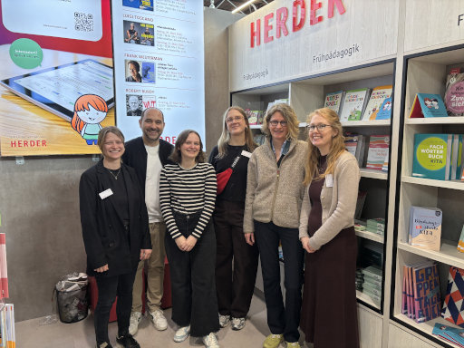 Eine Gruppe von Herder-Mitarbeitenden posieren vor dem Herderstand auf der Leipziger Buchmesse