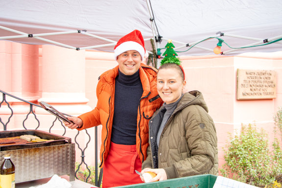 Der Geschäftsführer und die Head of People und Culture grillen Würstchen beim Nikolausgrillen vor dem Roten Haus