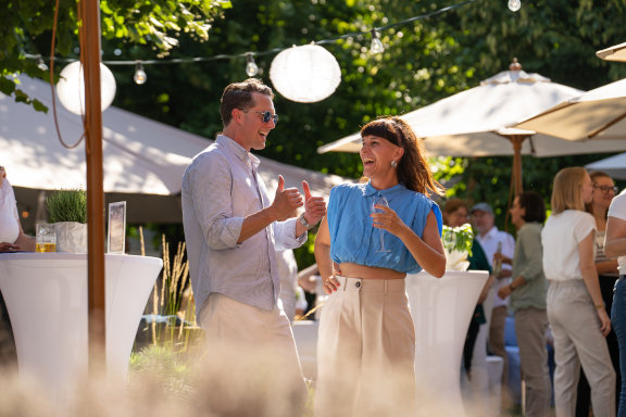 Der Geschäftsführer und eine Herder-Mitarbeitende lachen beim Sommerfest