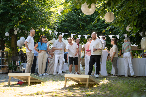 Mehrere Herder-Mitarbeitende vergnügen sich beim Sommerfest mit dem Spiel Cornhole