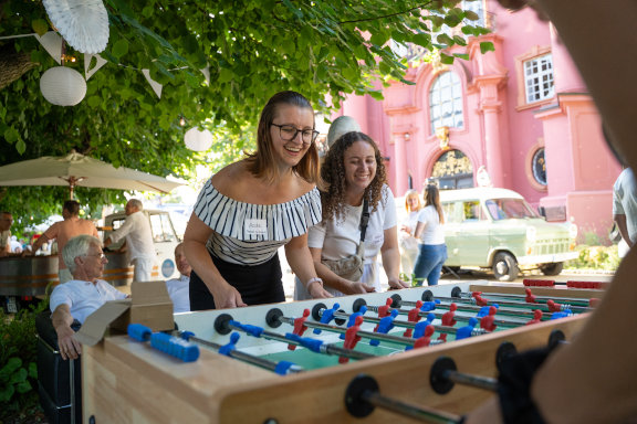 Zwei Herder-Mitarbeiterinnen spielen Tischkicker beim Sommerfest