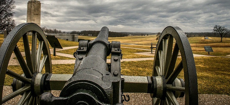 Eine Kanone auf Holzrädern zeigt Richtung Horizont.