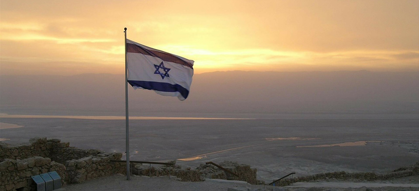 Die israelische Flagge weht auf einem Hügel mit Sonnenuntergang.