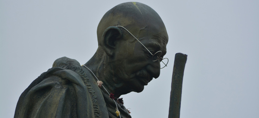 Es ist die Büste von Mahatma Gandhi zu sehen, ein Mann mit Glatze und Brille.