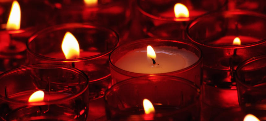 Brennende Teelichter in drei unterschiedlichen Reihen sind zu sehen, die man üblicherweise in einer Kirche sehen kann.