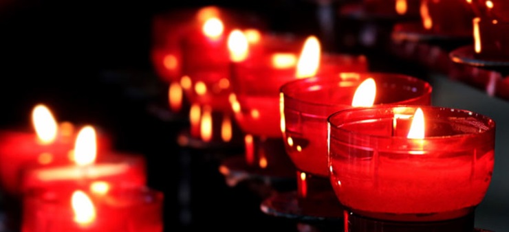 Brennende Teelichter in drei unterschiedlichen Reihen sind zu sehen, die man üblicherweise in einer Kirche sehen kann.
