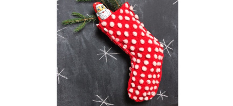 Man kann einen roten Strumpf mit weißen Punkten sehen, aus den ein Schokoladen-Nikolaus ragt.