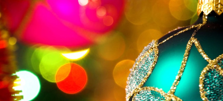 Eine grüne Weihnachtskugel ist im Vordergrund, verschwommene weitere im Hintergrund.