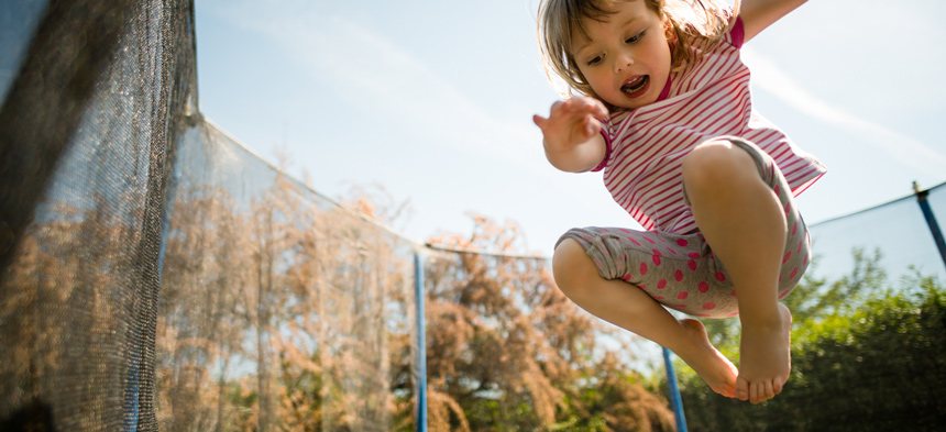 Mädchen springt auf einem Trampolin in die Luft.