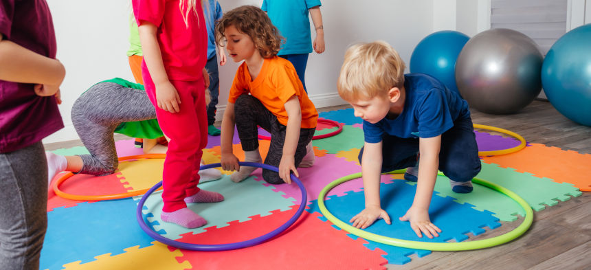 Kinder bewegen sich mit Reifen und Bällen