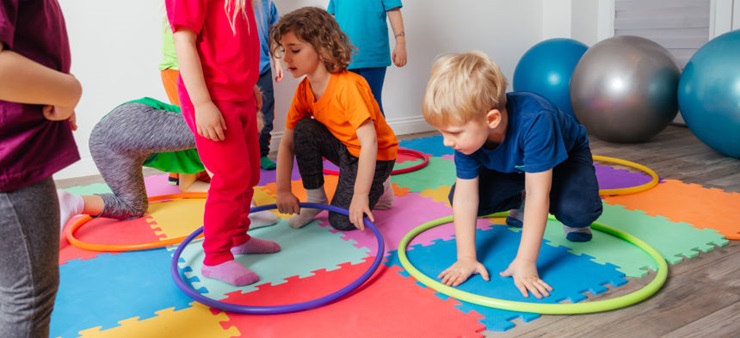 Kinder bewegen sich mit Reifen und Bällen