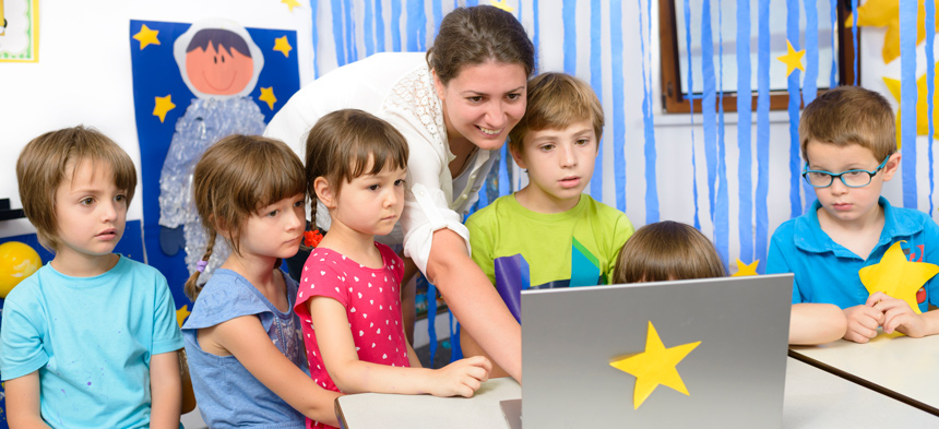 Erzieherin zeigt Kindern Inhalte auf einem Laptop