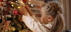 Mädchen schmückt einen Tannenbaum