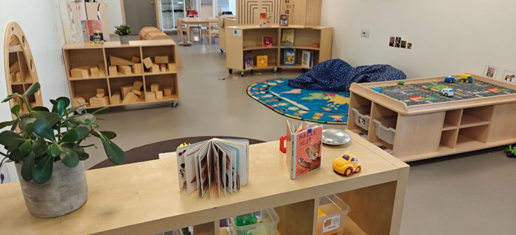 Es ist das Innere eines Kindergartenzimmers zusehen, mit Spielecken und Regalen.