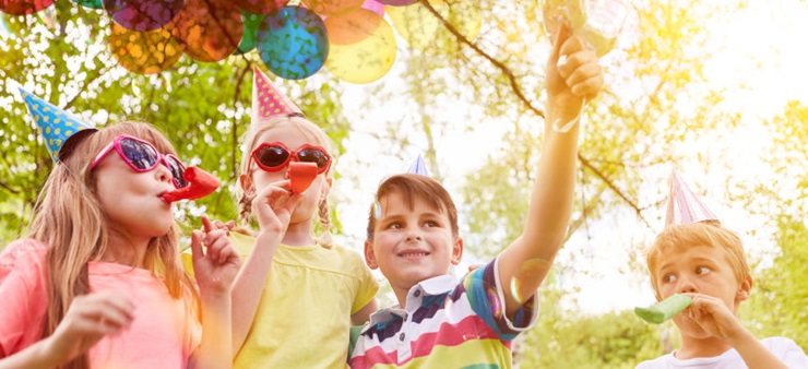 Kinder mit Sonnenbrillen feiern draußen im Garten.