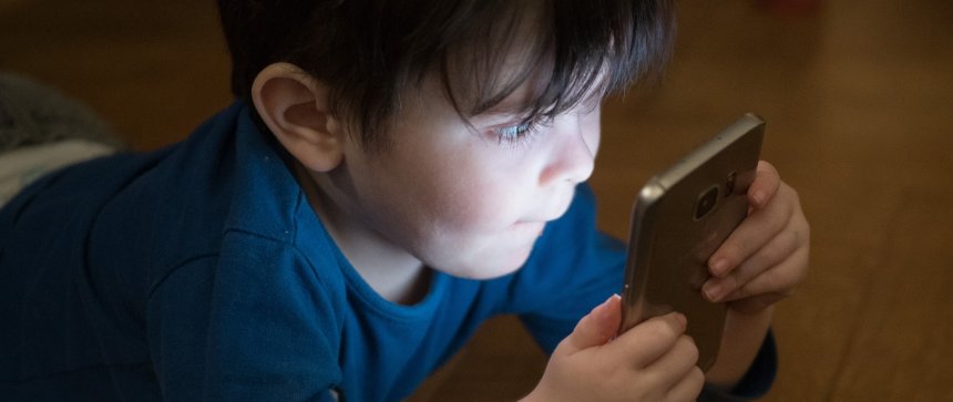 Ein Kind starrt auf einen Smartphone-Bildschirm.