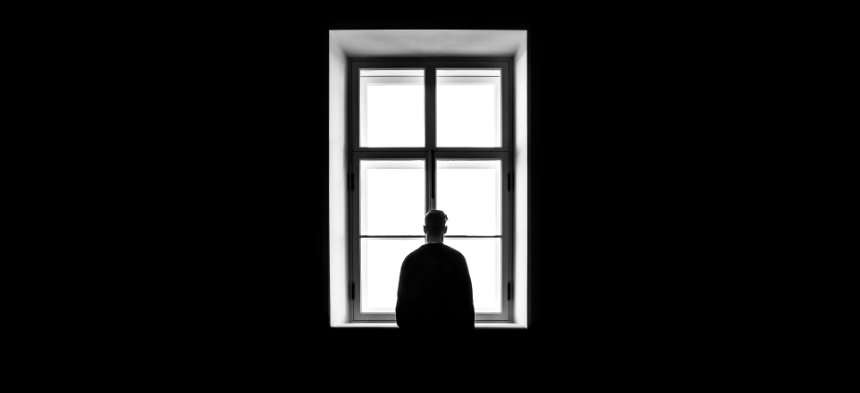 Ein Mann steht vor einem großen Fenster und schaut hinaus.