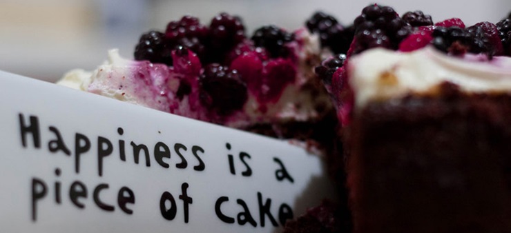 Ein Beerenkuchen und ein Schildchen mit der Aufschrift Happiness is a piece of cake