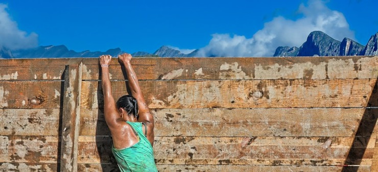 Eine junge Frau zieht sich aus Trainingszwecken an einer Wand hoch.