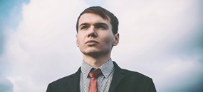 Ein junger Mann im Anzug schaut zuversichtlich in die Ferne.