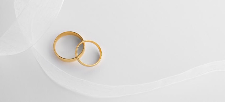 ein kleiner, goldener Ring liegt schräg auf einem großen, goldenen Ring.