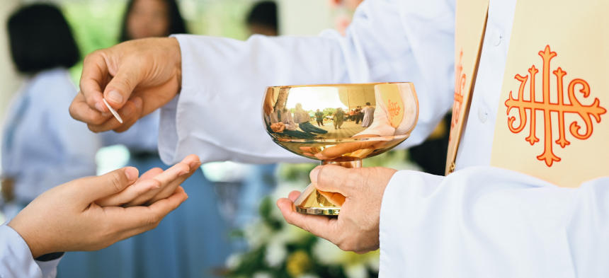 Rosa Rosen umrahmen ein Jesuskreuz.