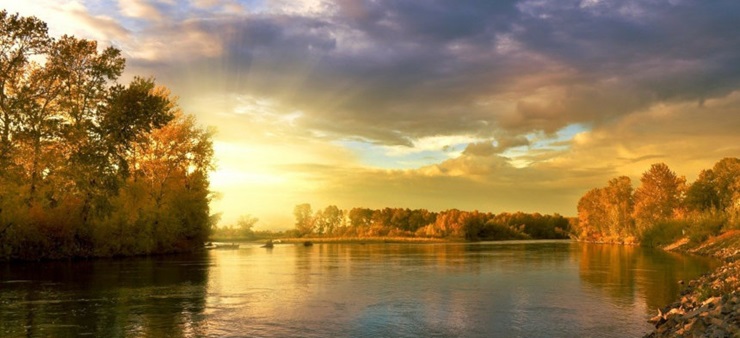 Die Sonne geht an einem See auf.