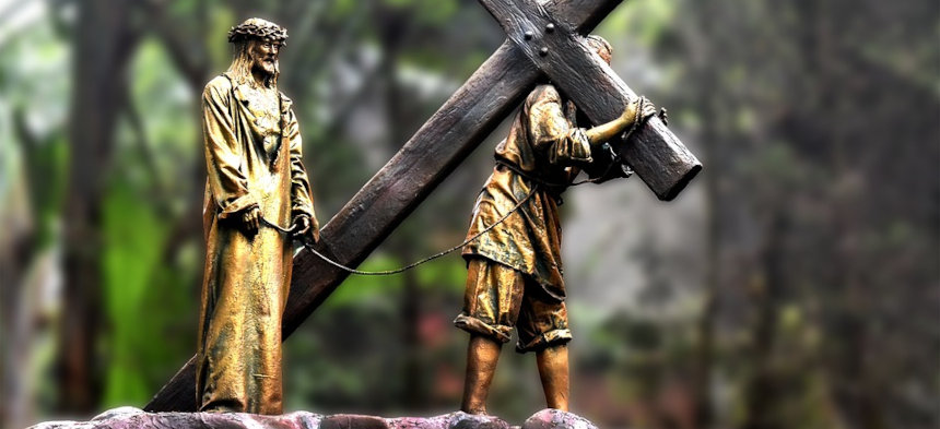 Eine goldfarbene Statue von Jesus trägt das Kreuz.