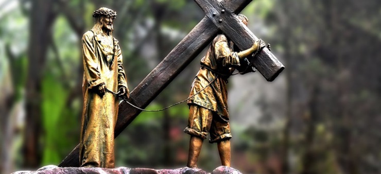 Eine goldfarbene Statue von Jesus trägt das Kreuz.