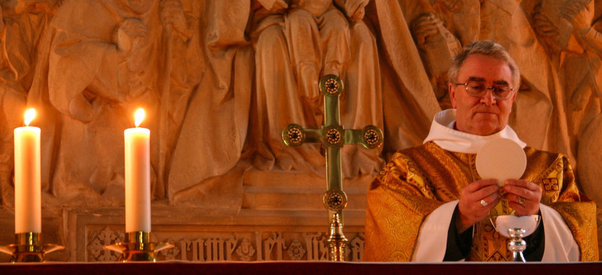 Priester am Altar mit Hostie