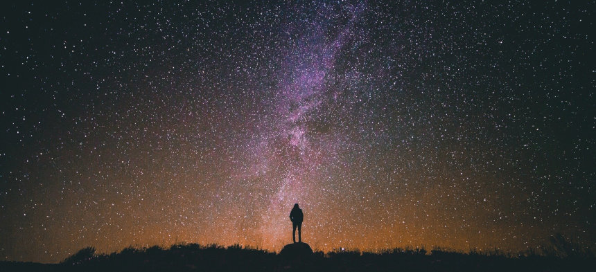 Mann steht vor einem Sternenhimmel.