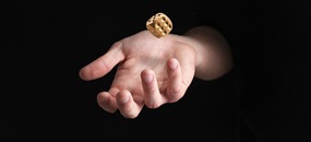 Eine Hand wirft einen goldenen Würfel in die Luft.