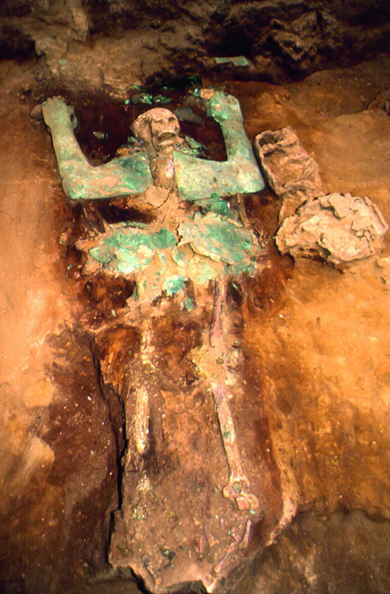 Grab der ersten Priesterin von San José de Moro. Die Tote lag in einem Sarg, der vermutlich aus Schilfrohr bestand und mit Kupferplatten in Form menschlicher Gliedmaßen verziert war. Bei der Ausgrabung lagen die Platten unmittelbar auf dem Skelett: der Befund im Detail.