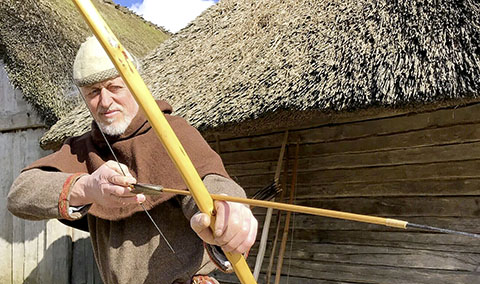 Der Living-History-Darsteller Reinhard Erichsen zeigt den Besuchern von Haithabu den Umgang mit dem Bogen.