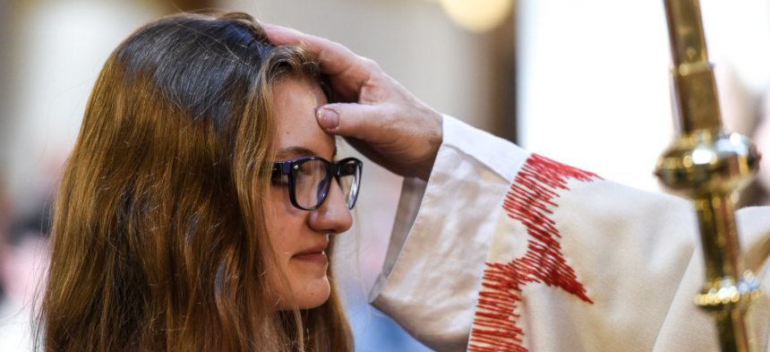 Ein junges Mädchen empfängt von einem Priester das Sakrament der Firmung 