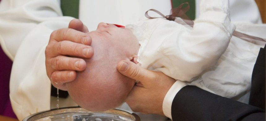 Ein Priester tauft einen Säugling