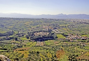 Abb. 1 Ein Panoramabild des Tals von Knossos. Grüne Felder und moderne Siedlungen, in der Mitte die Ruinen des bronzezeitlichen Palastes.