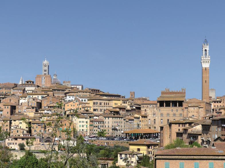In prachtvoller Panoramalage auf drei Hügeln: Siena, von Südosten gesehen. Aus der Silhouette ragen der Dom (links) und der Rathausturm (rechts) heraus.