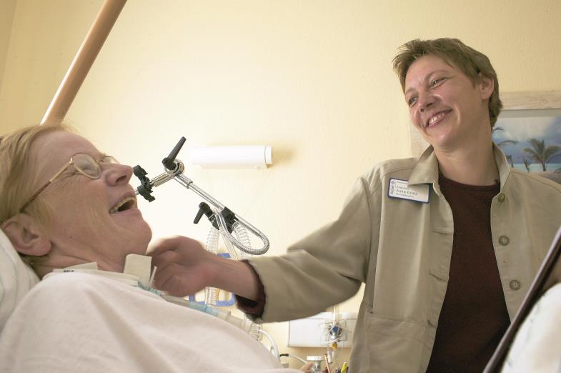 Eine Seelsorgerin in Bielefeld sitzt am Bett einer dauerbeatmeten Patientin.