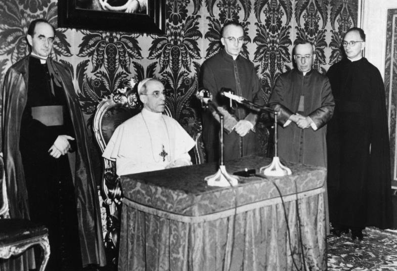 Papst Pius XII. an einem Tisch mit Mikrofon