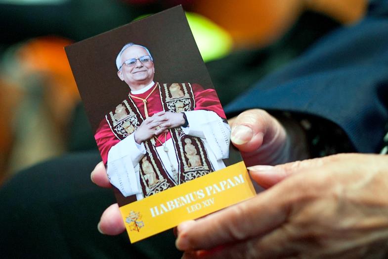 Eine Gläubige hält eine Broschüre mit Papst Leo XIV. in der Hand