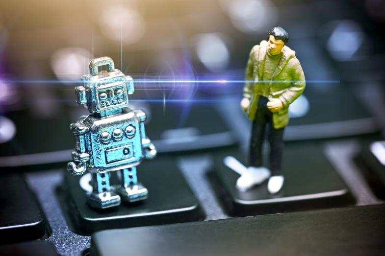 Kleine Figuren eines Roboters und eines Mannes auf einer Computer-Tastatur