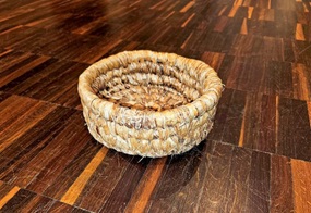 Kleine geflochtene Schale aus Seegras auf Holzboden