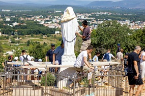 Menschen reinigen eine weiße Marien-Statue