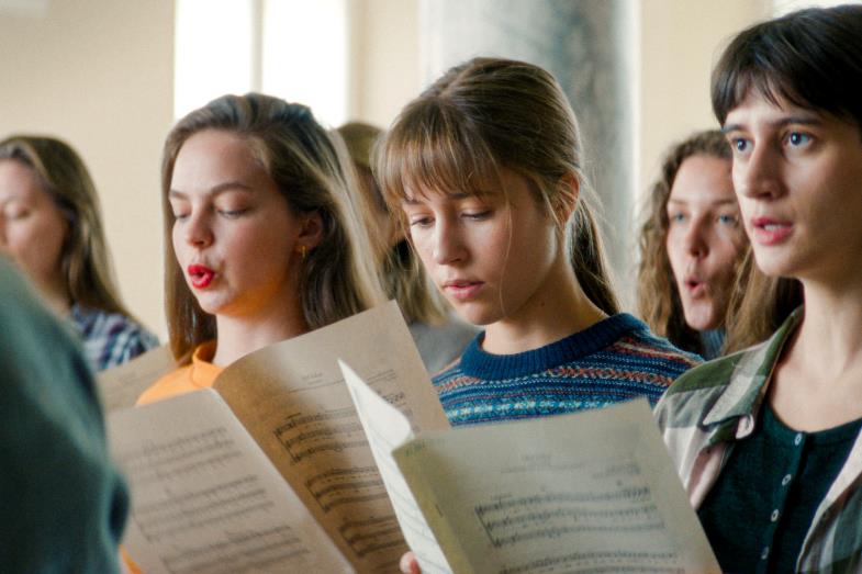 Chor aus jungen Frauen, singend und Noten in den Händen haltend