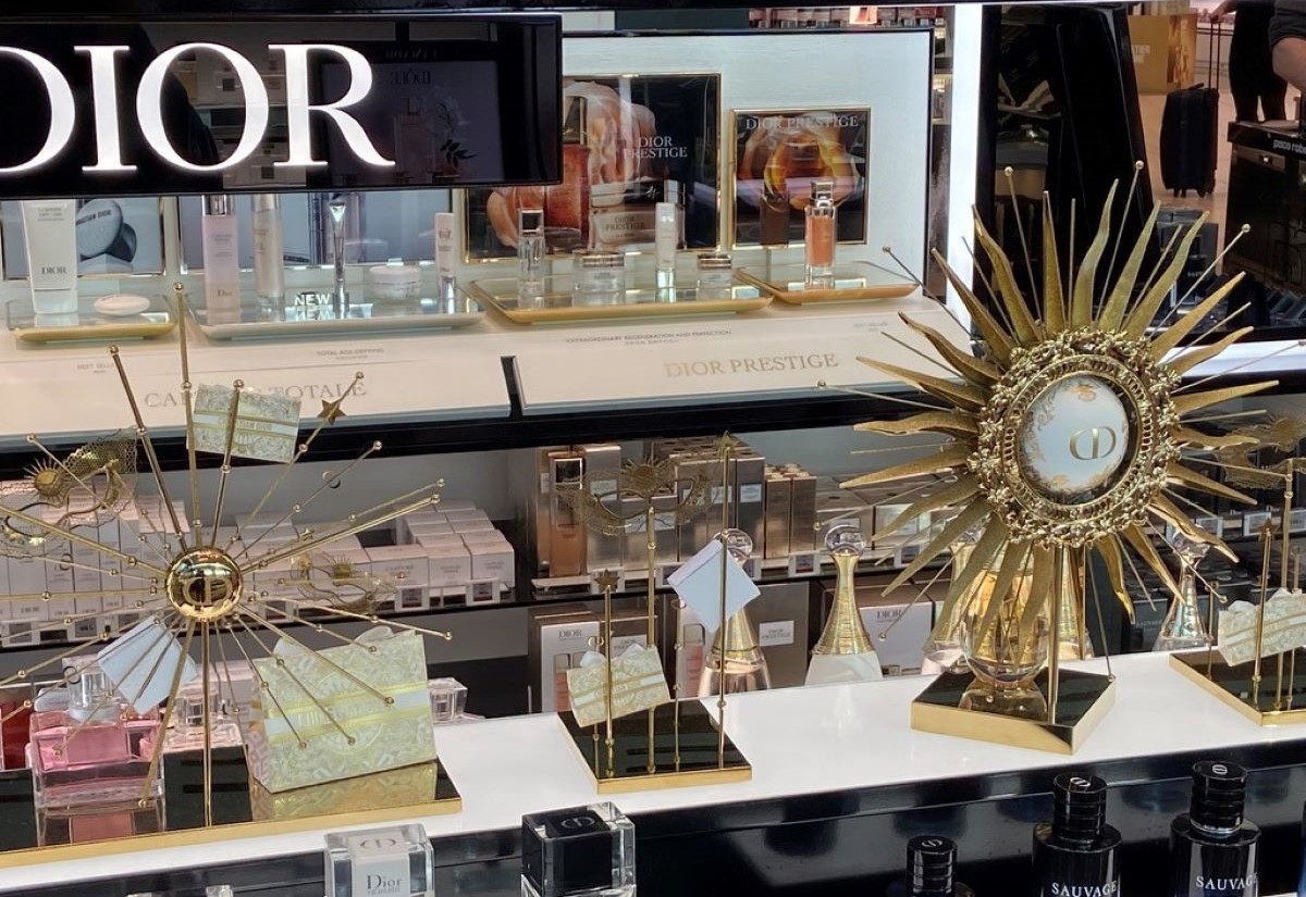 Schaufenster in Rom mit goldener Monstranz, eingerahmt von Parfumangeboten der Marke Dior.