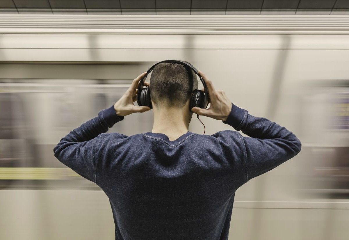 Mann an einem Bahnsteig mit Kopfhörern