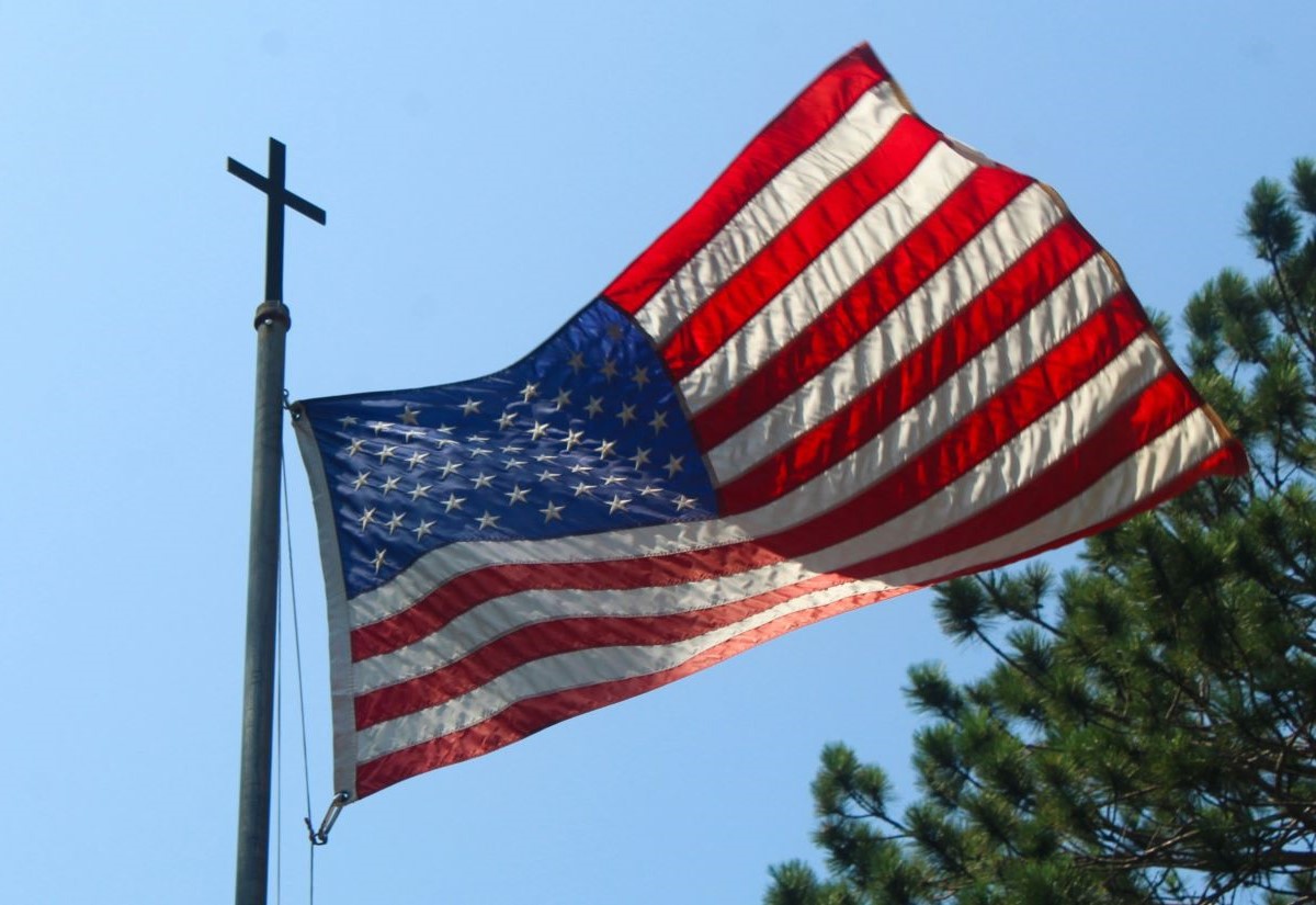 Amerikanische Flagge unter einem Kreuz auf der Fahnenstange
