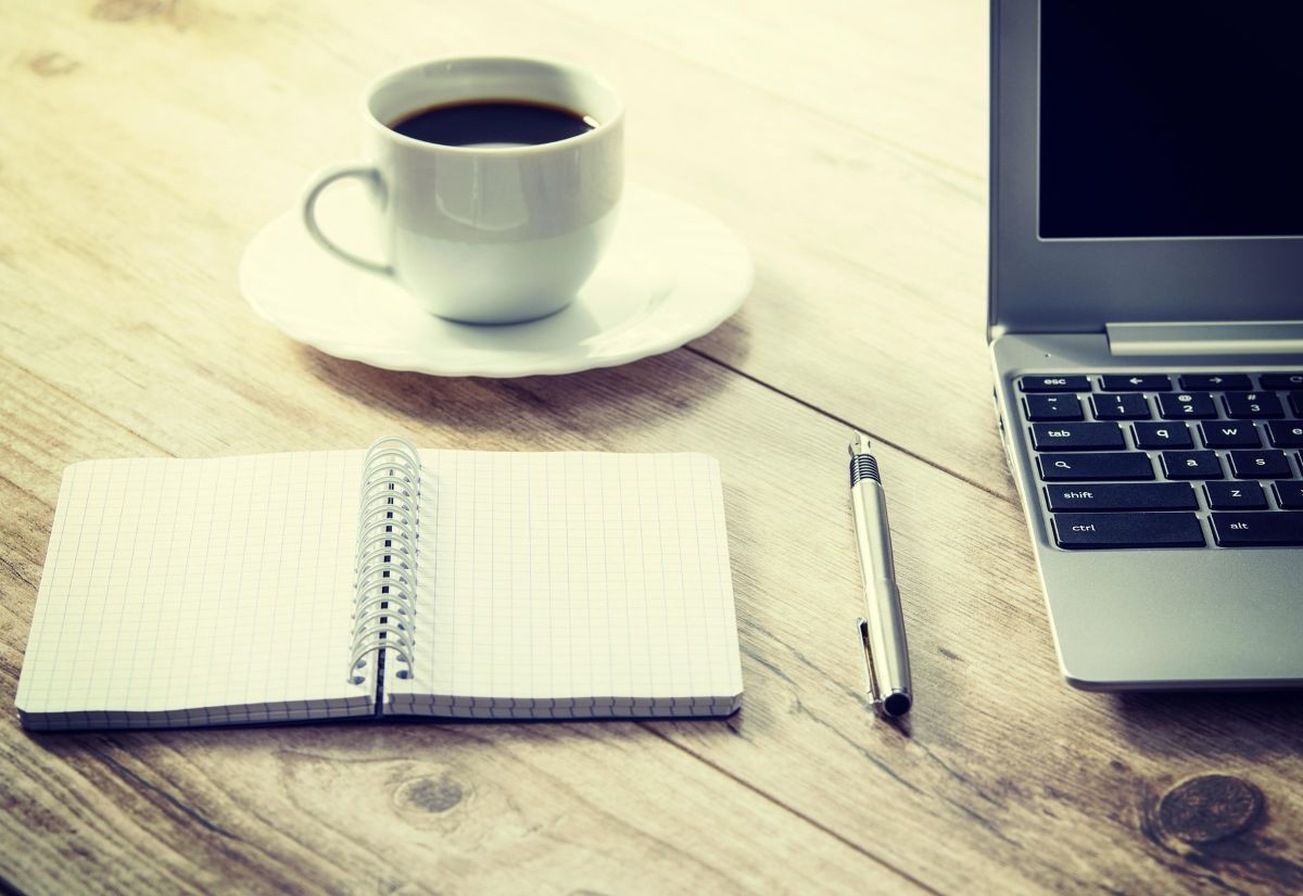 Schreibblock, Laptop und Kaffeetasse
