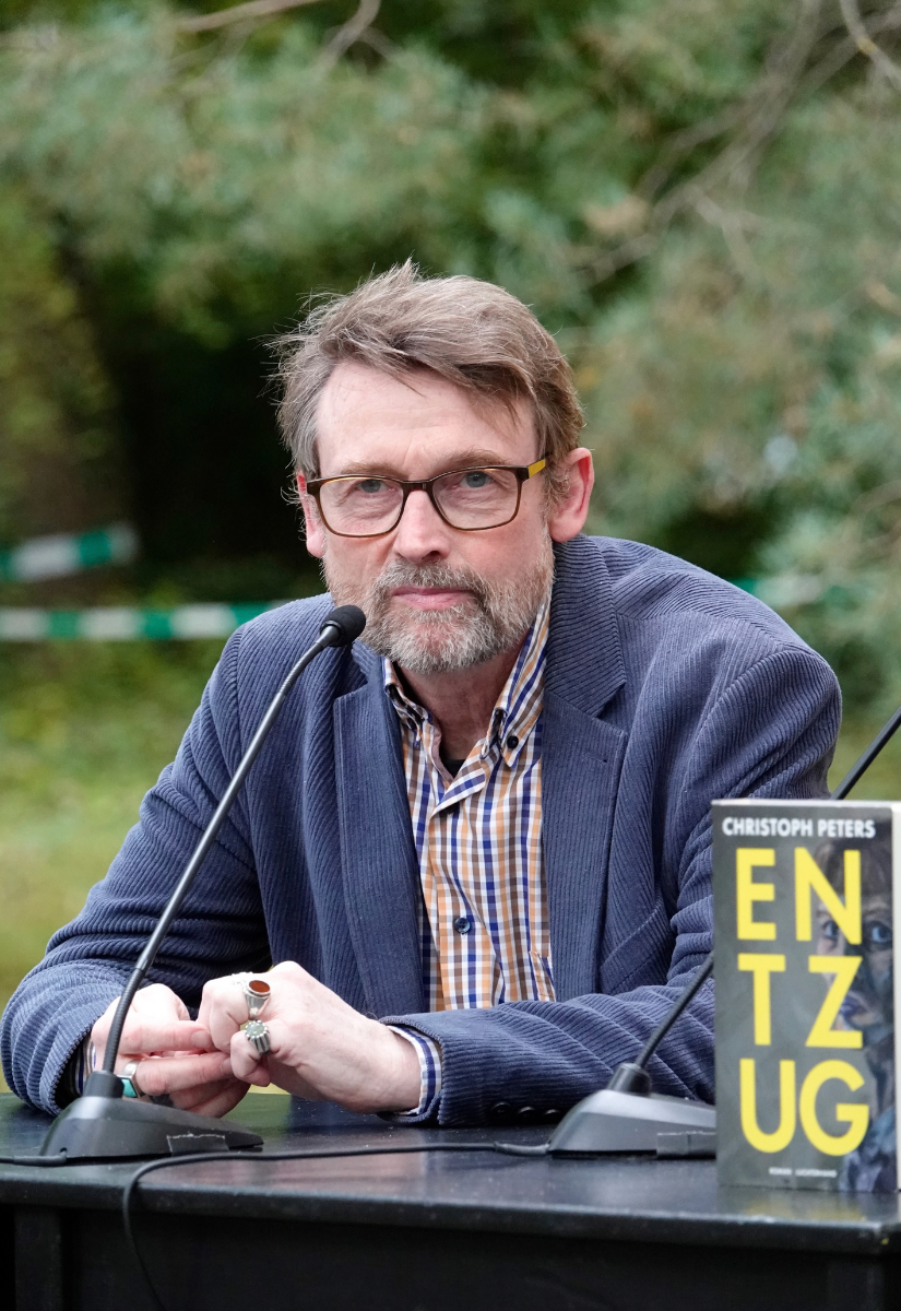 Ein Bild vom Schriftsteller Christoph Peters mit seinem Buch "Entzug", auf dessen Cover ein Selbstportrait abgebildet ist 
